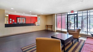 A lobby with a reception desk, seating area, and large windows with blinds. - Suburban Studios Macon North (Macon)