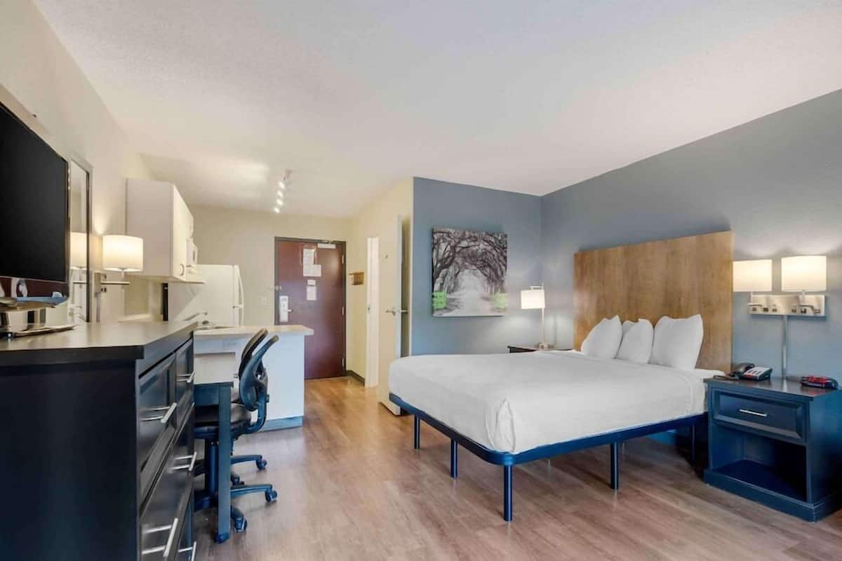 A hotel room with a bed, desk, chair, and bedside tables.