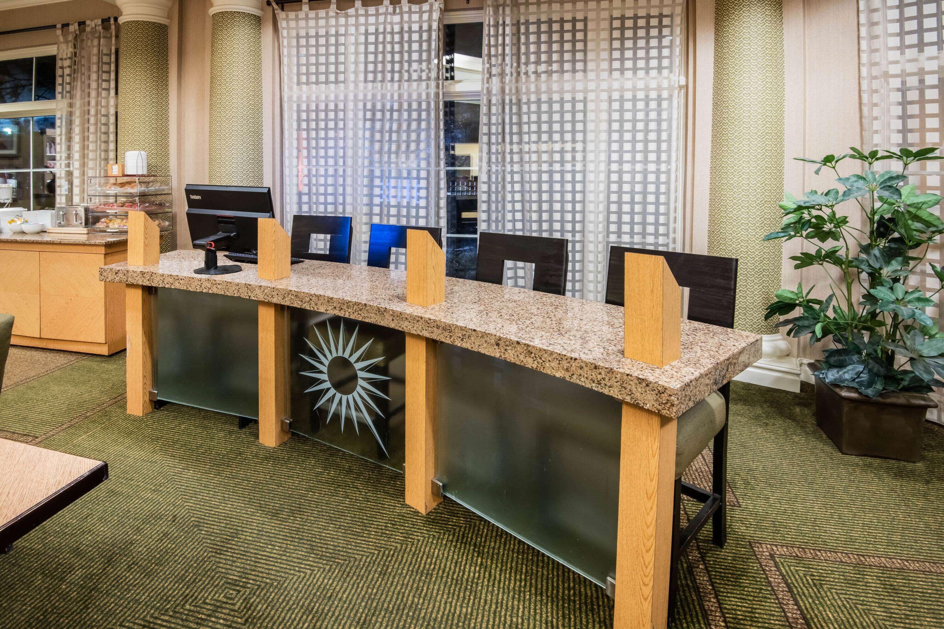 A reception desk with a modern design, a coffee station, and a large potted plant.
