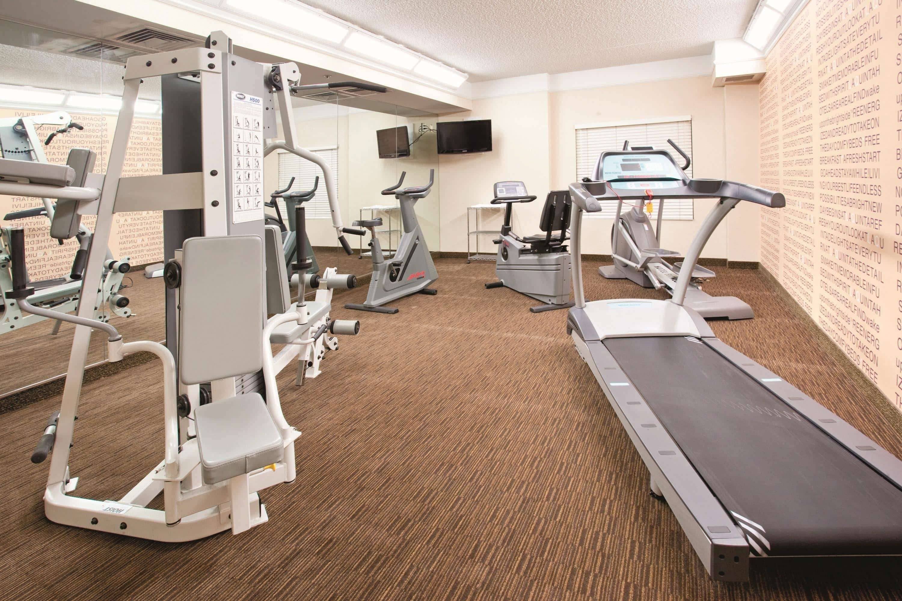 A gym with cardio machines, weight stations, and a treadmill.