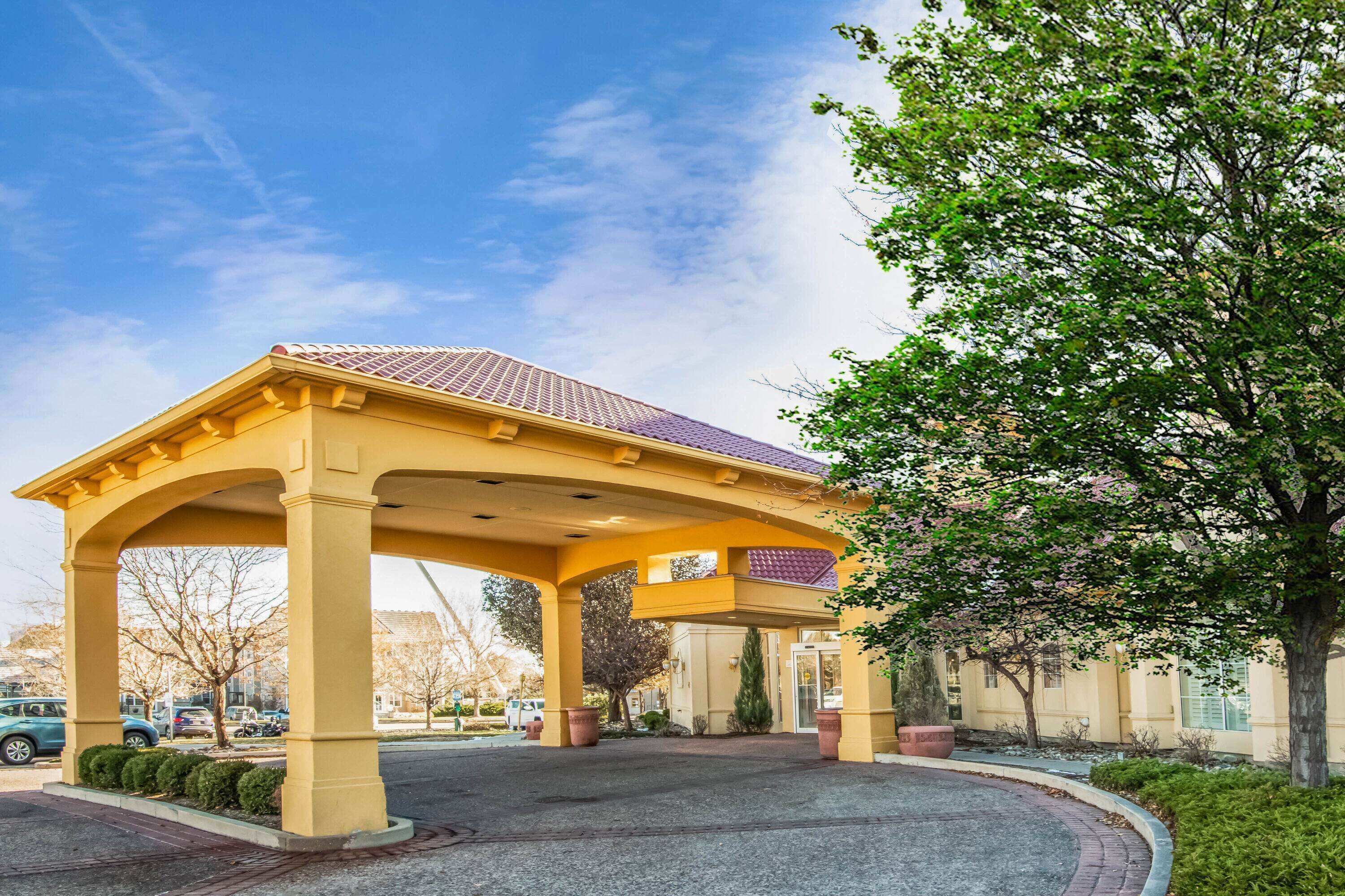 A yellow pavilion with a tiled roof, surrounded by a landscaped area with trees and shrubs.