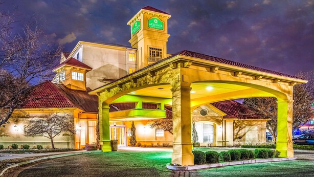 Um hotel com uma torre do relógio imponente, entrada coberta e fachada bem iluminada.