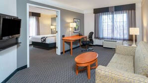 Une chambre d’hôtel équipée d’un lit, d’un bureau, d’une chaise, d’un canapé, d’une télévision et d’une fenêtre avec des rideaux.