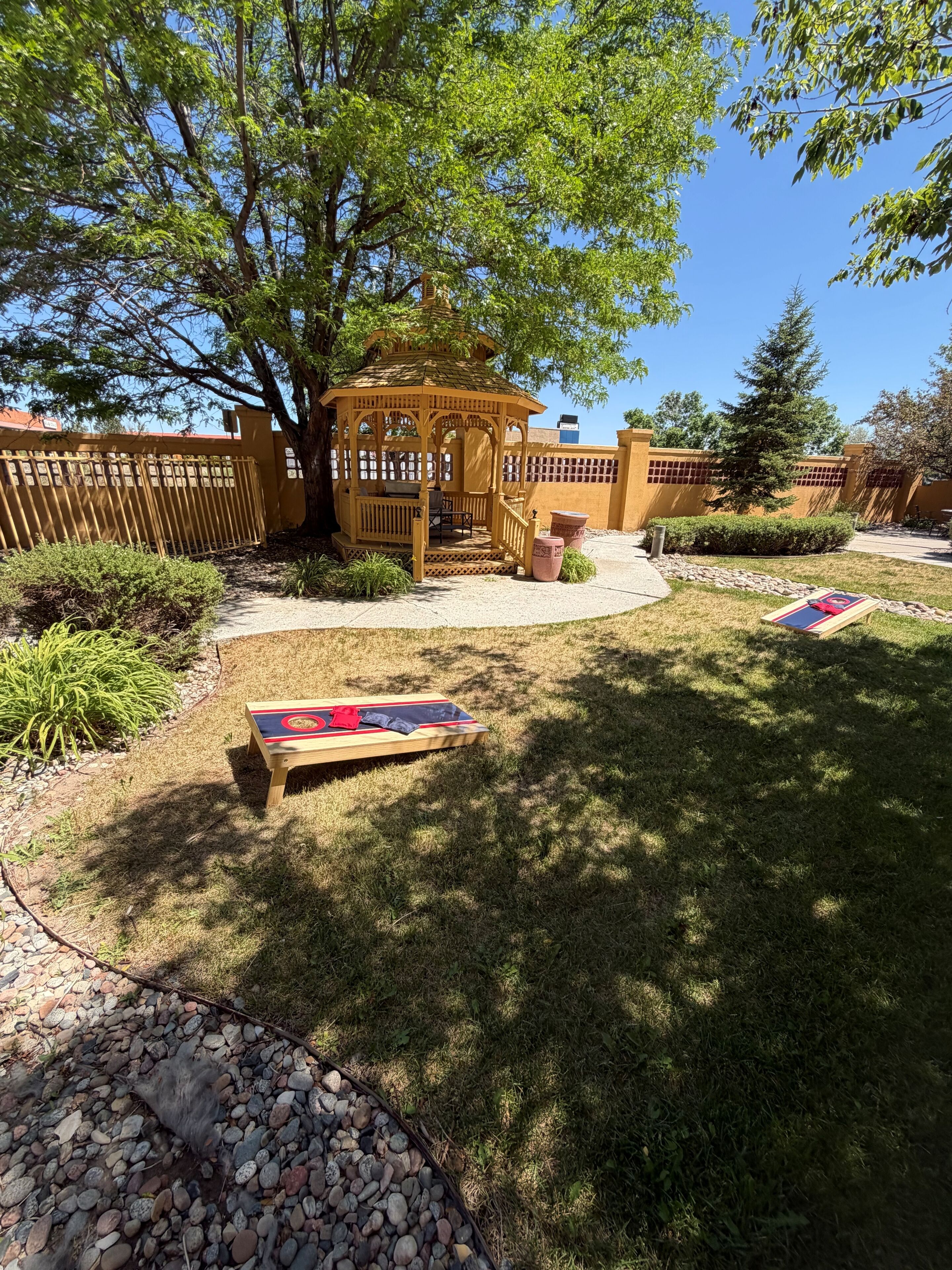 A wooden gazebo, a picnic table, and a small garden area with a pathway and potted plants.