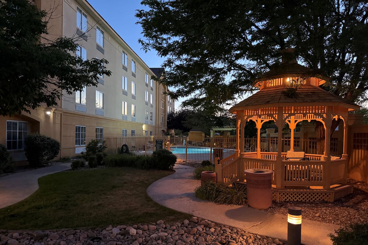 A gazebo with a wooden structure and a pool in the background.