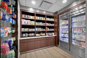 Uma seção de mercearia bem abastecida, com prateleiras cheias de lanches, bebidas e produtos embalados.