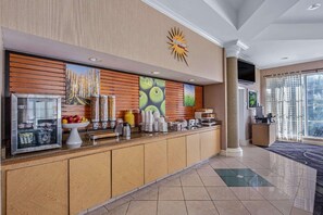 Een hotel receptie met een balie, een fruitmand en een groot zonvormig bord.
