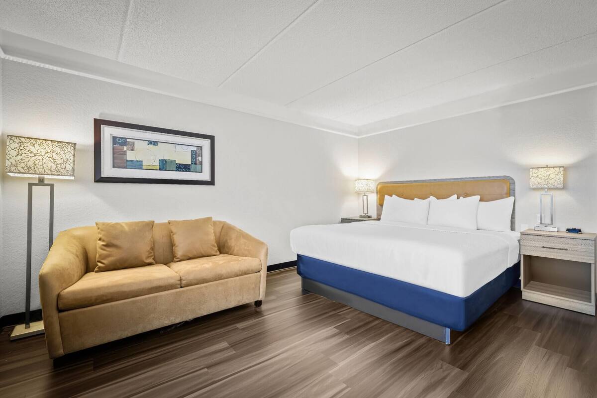 Ein Hotelzimmer mit einem Bett, einem Schlafsofa und zwei Nachttischen mit Lampen.