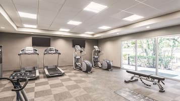 A gym with treadmills, elliptical machines, and a bench.
