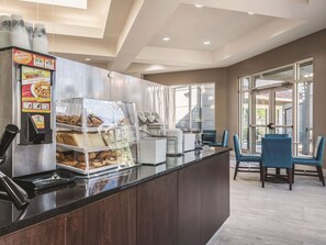 A breakfast bar with a coffee machine, a waffle display, and a glass display case with pastries. - La Quinta Inn & Suites by Wyndham Orlando Lake Mary (Lake Mary)
