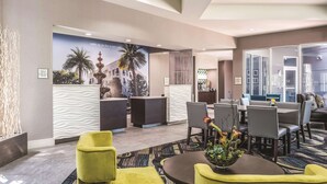 A hotel lobby with a reception desk, seating area, and a mural of a cityscape.