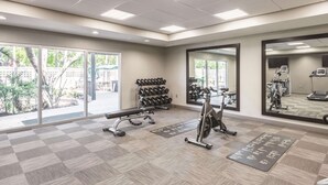 A gym with exercise equipment, a bench, and a mirrored wall.