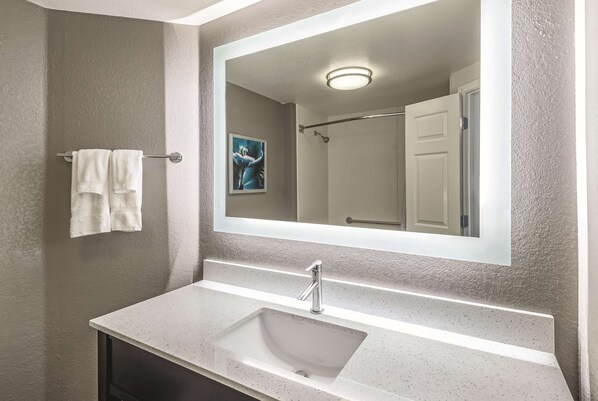 Un baño con un lavabo blanco, un espejo grande y un toallero.
