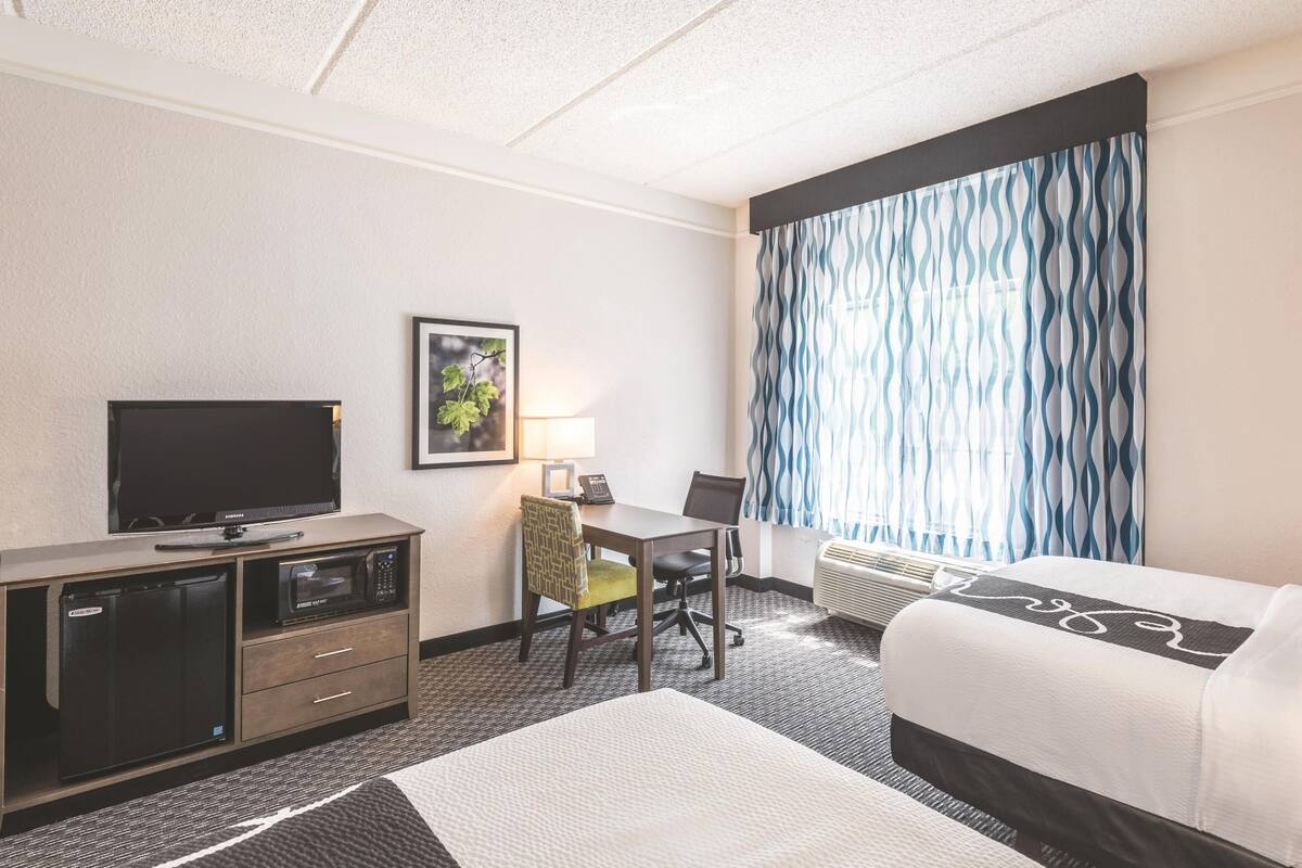 Ein Hotelzimmer mit Bett, Schreibtisch mit Stuhl, Fernseher, Mikrowelle und Heizung.