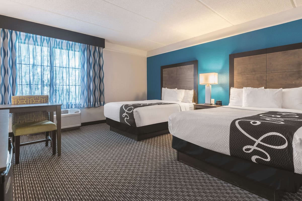 Ein Hotelzimmer mit zwei Betten, einem Schreibtisch und einem Sessel.