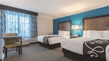 Quarto de hotel com duas camas, uma escrivaninha e uma cadeira.