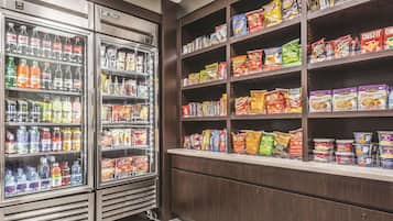 A snack and beverage section with refrigerated drinks and shelves stocked with various snacks and cereals.