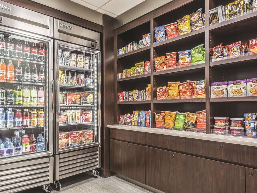 A snack and beverage section with refrigerated drinks and shelves stocked with various snacks and cereals.