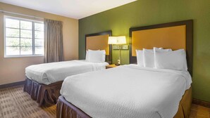 Habitación de hotel con dos camas, un ventanal con cortinas y una pared verde.