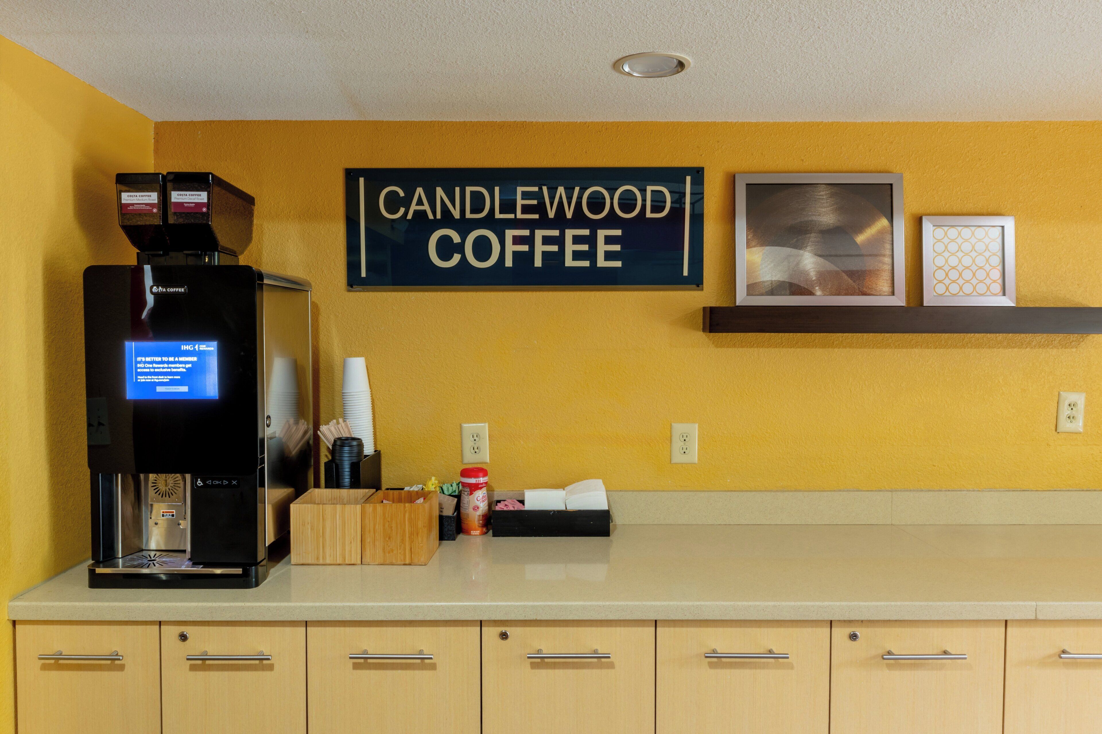 A coffee machine, a sign reading 'CANDLEWOOD COFFEE,' and a shelf with framed pictures.