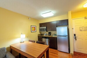 A compact kitchen with a dining table, chairs, a microwave, a refrigerator, and a dishwasher.