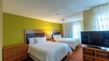 Habitación de hotel con dos camas, televisión, escritorio y lámpara.