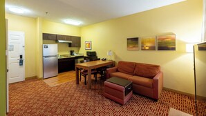 Un espacio habitable compacto con kitchenette, comedor, sofá y alfombra estampada.