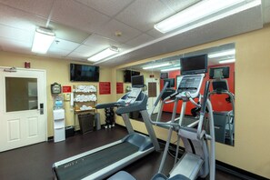 Une salle de sport équipée de tapis de course, d’un distributeur d’eau et d’un téléviseur fixé au mur.