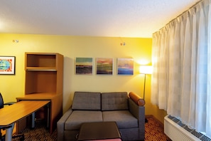 Une chambre d’hôtel avec un canapé, une table, une lampe et trois tableaux au mur.