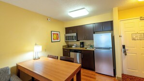 Una cocina compacta con una mesa de comedor, sillas, microondas, refrigerador y lavavajillas.