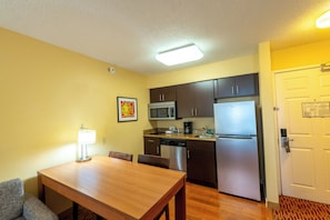 Una cocina compacta con una mesa de comedor, sillas, microondas, refrigerador y lavavajillas.
