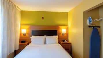 Habitación de hotel con cama, lámparas de noche, teléfono y una tabla de surf.