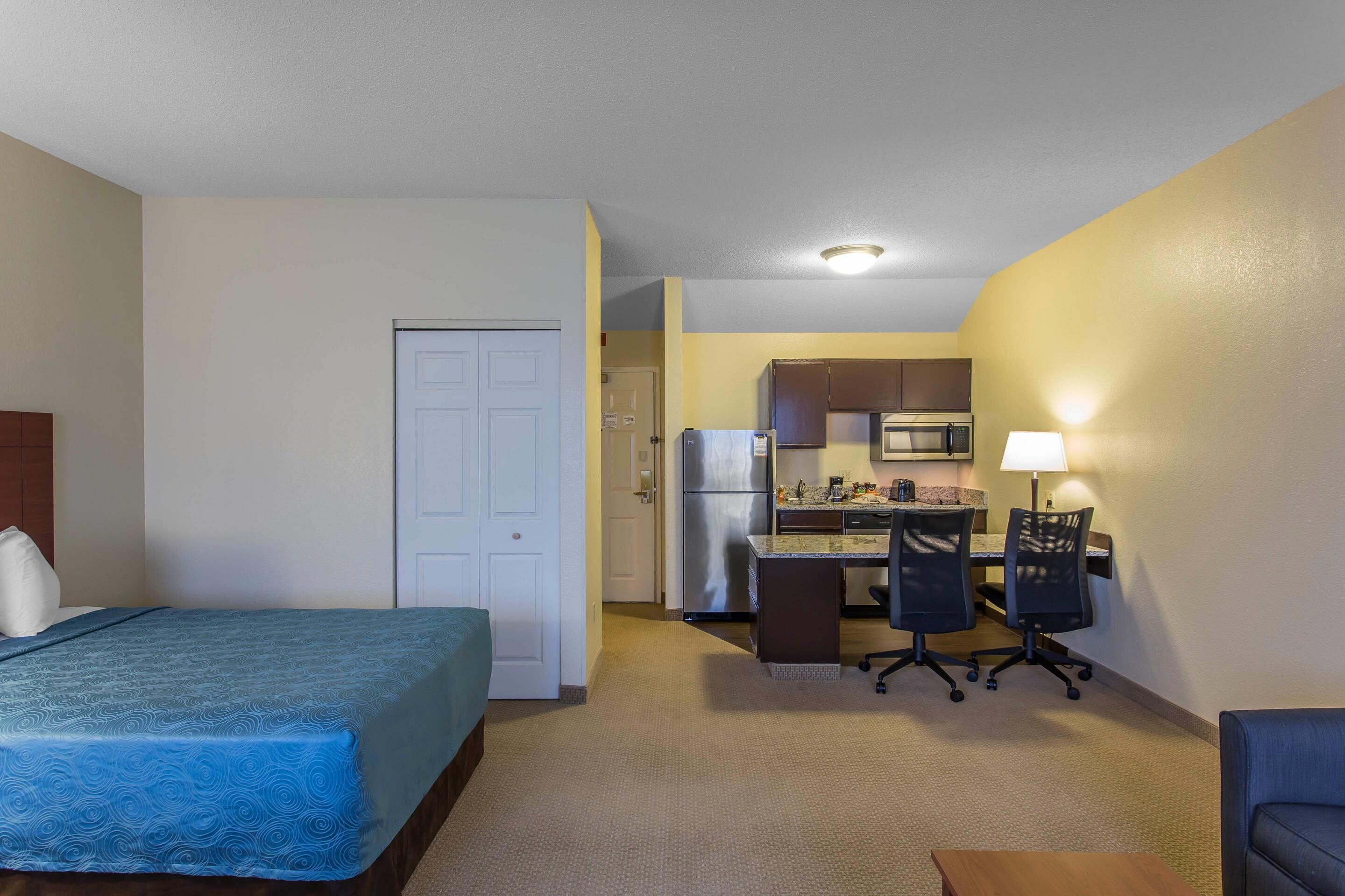 Una habitación de hotel con cama, escritorio, silla, microondas y refrigerador.