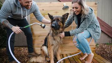 A wooden deck with a dog being showered by two people.