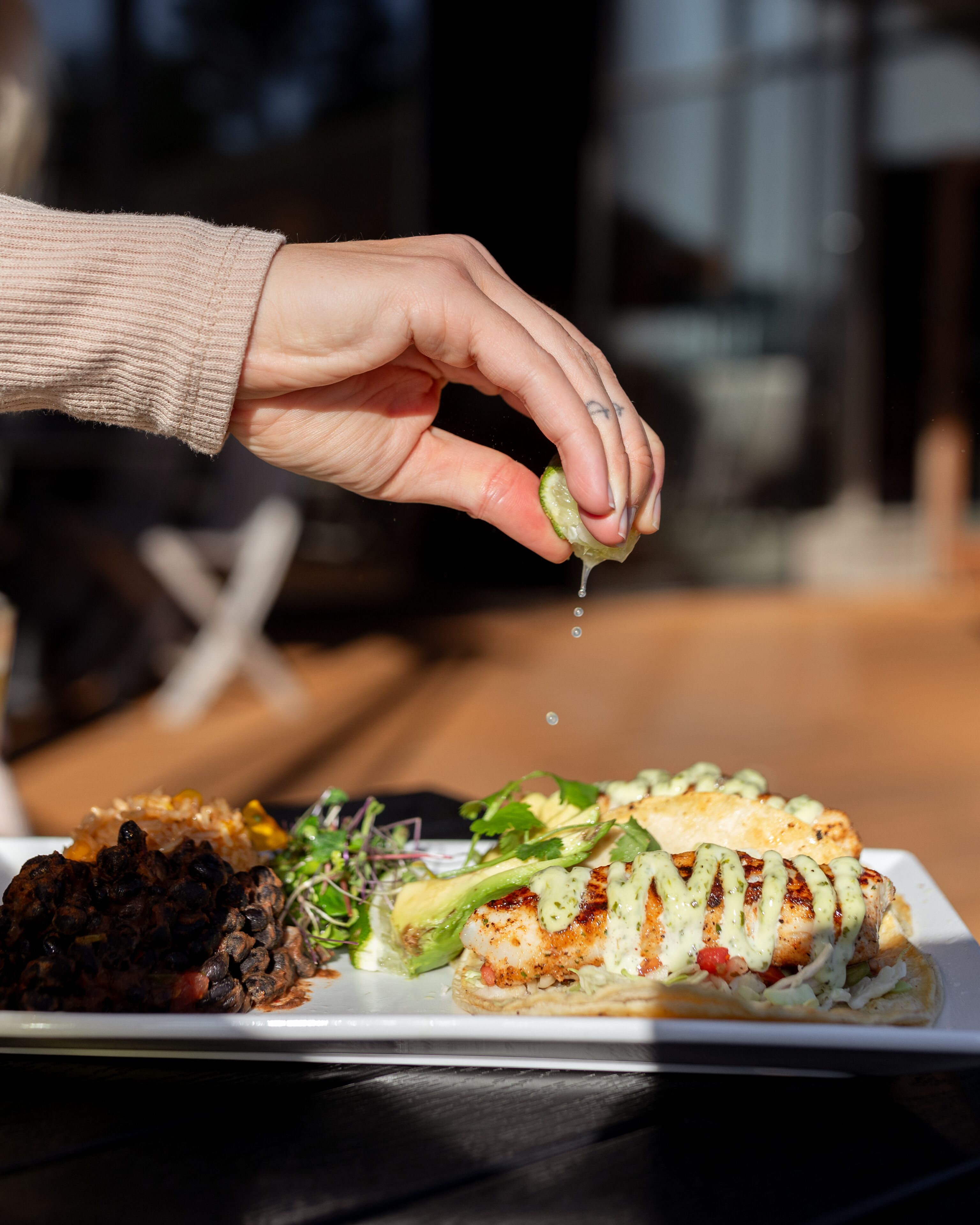 A hand squeezing a lime over a plate of food.