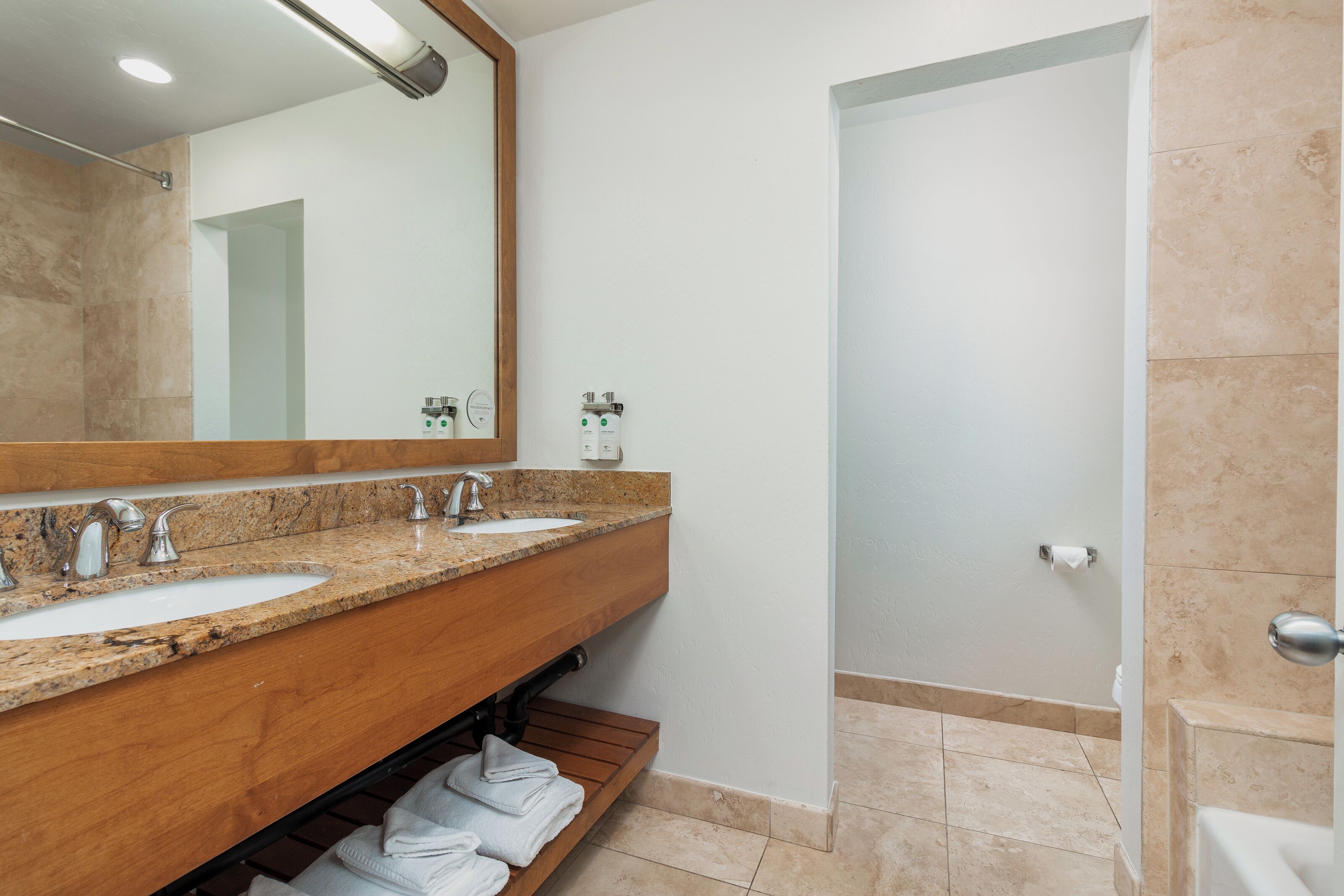 A bathroom with two sinks, a mirror, and a shower area.