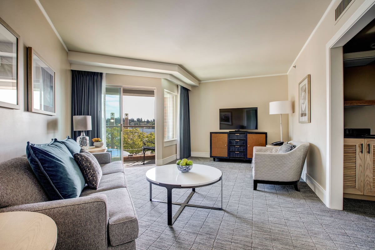 Una habitación de hotel moderna con sofá, sillón, una mesita redonda y televisión.