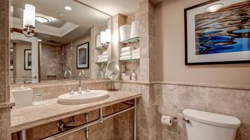 A modern bathroom with a large mirror, a sink, a toilet, and shelves with towels.