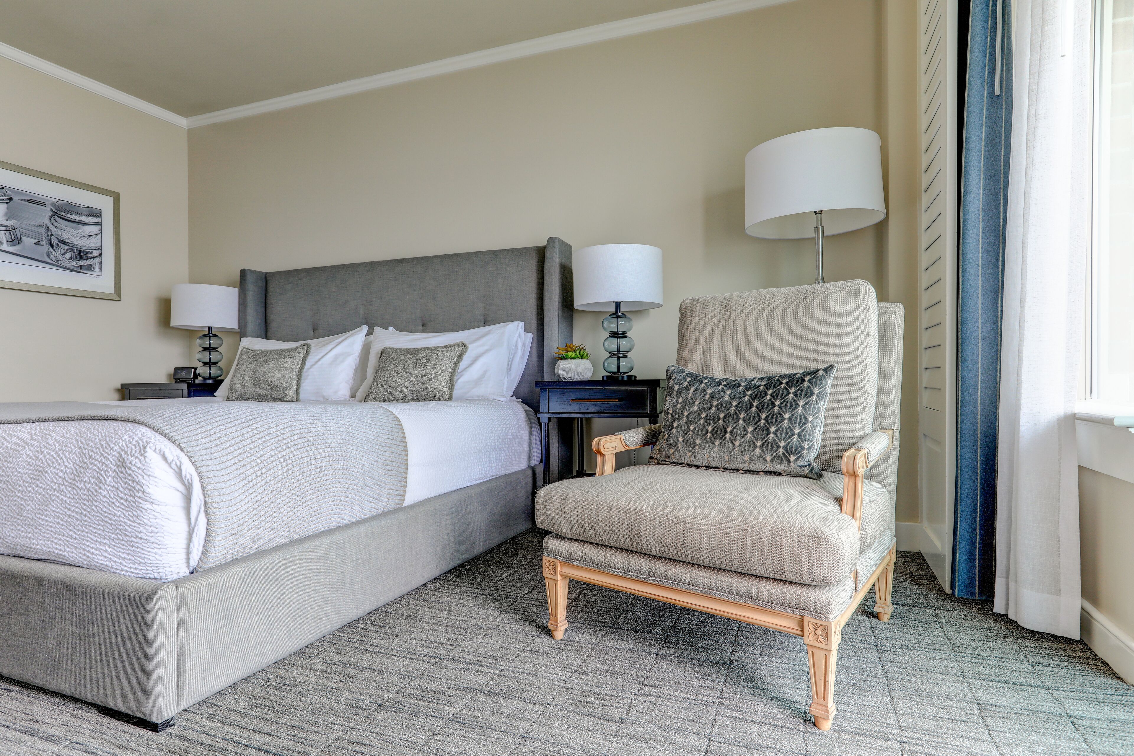 Una habitación de hotel con una cama, una silla, una mesita de noche y una lámpara.