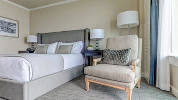 Una habitación de hotel con una cama, una silla, una mesita de noche y una lámpara.