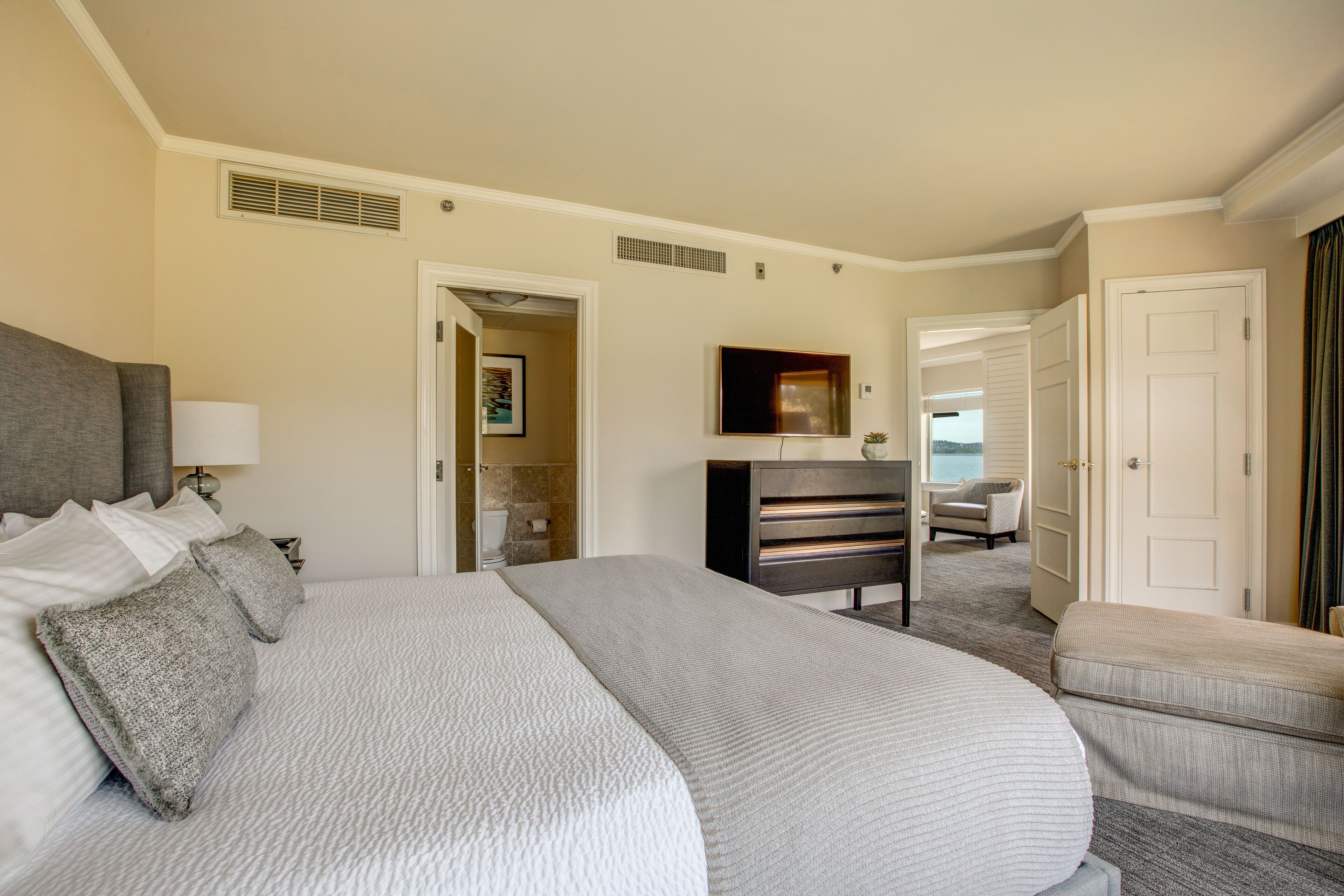 A hotel room with a large bed, a desk, a chair, and a bathroom visible through an open door.