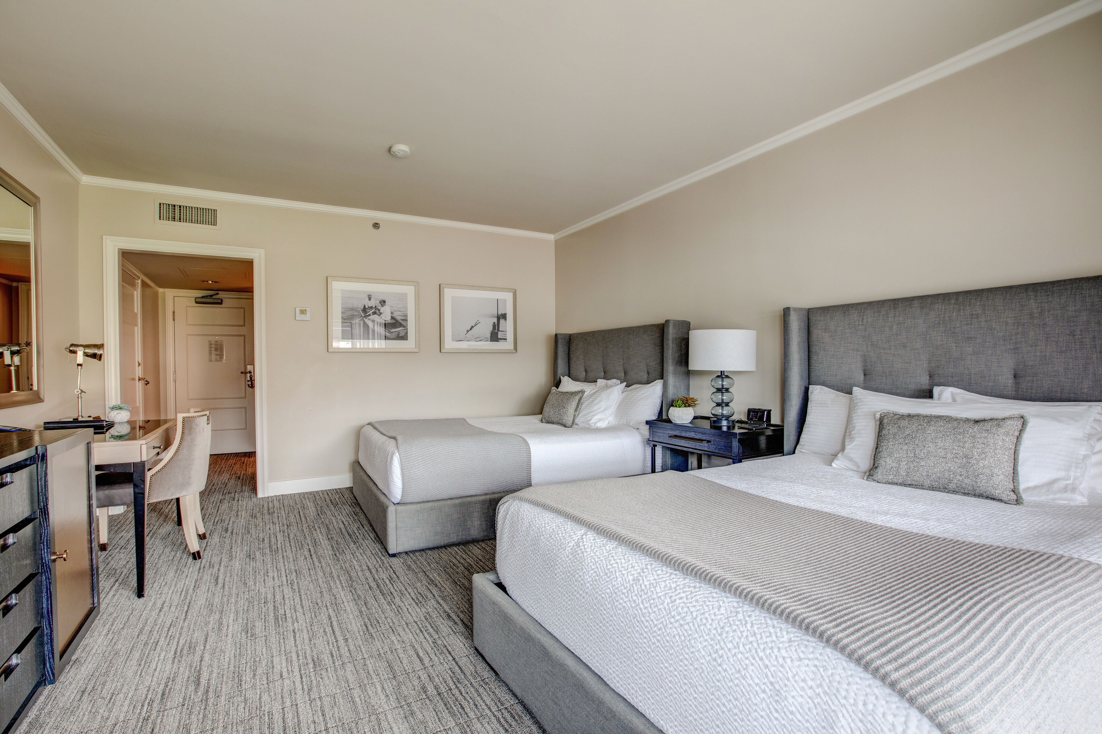 A hotel room with two beds, a desk, and a chair.