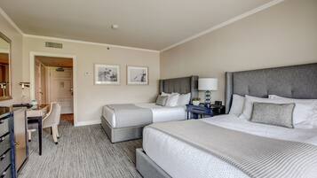 A hotel room with two beds, a desk, and a chair.