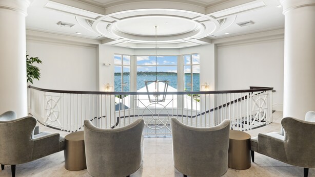 A spacious balcony with a view of the sea, furnished with grey chairs and a small table, and a white railing. - The Woodmark Hotel & Still Spa on Lake Washington (Kirkland)