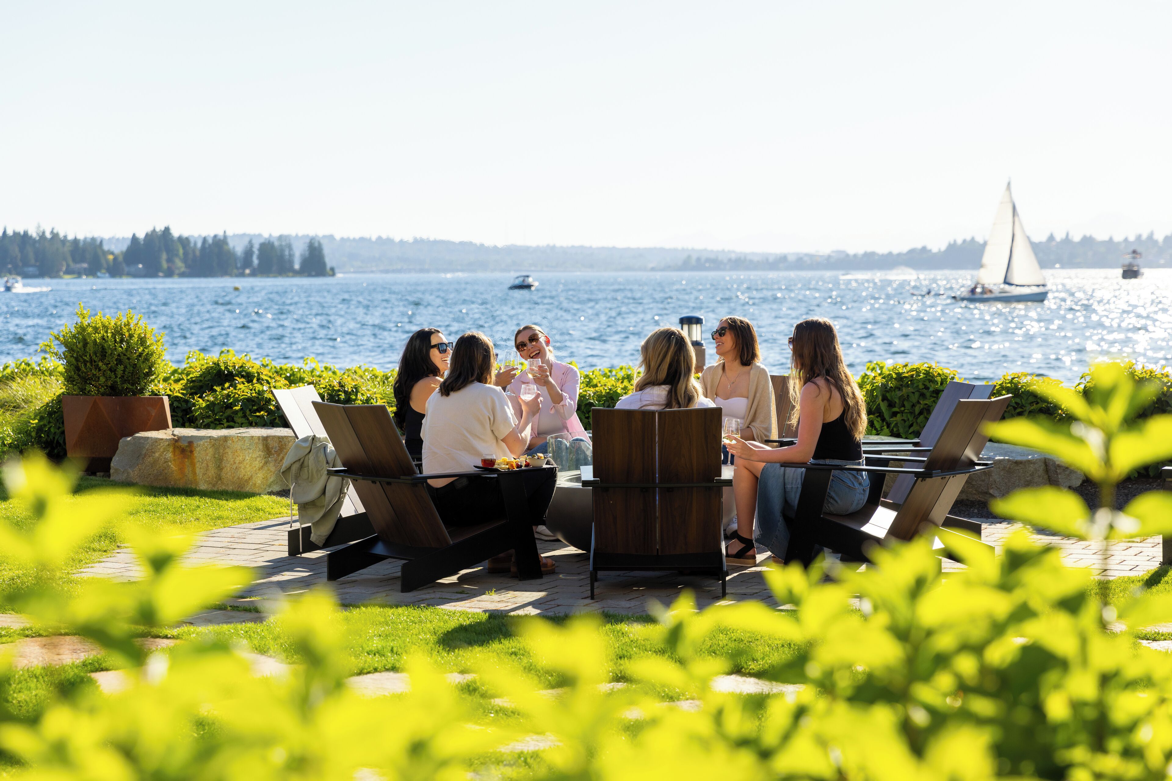 Un grupo de personas sentadas al aire libre, con vista a un lago y veleros.