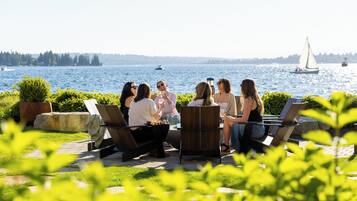 Un grupo de personas sentadas al aire libre, con vista a un lago y veleros.