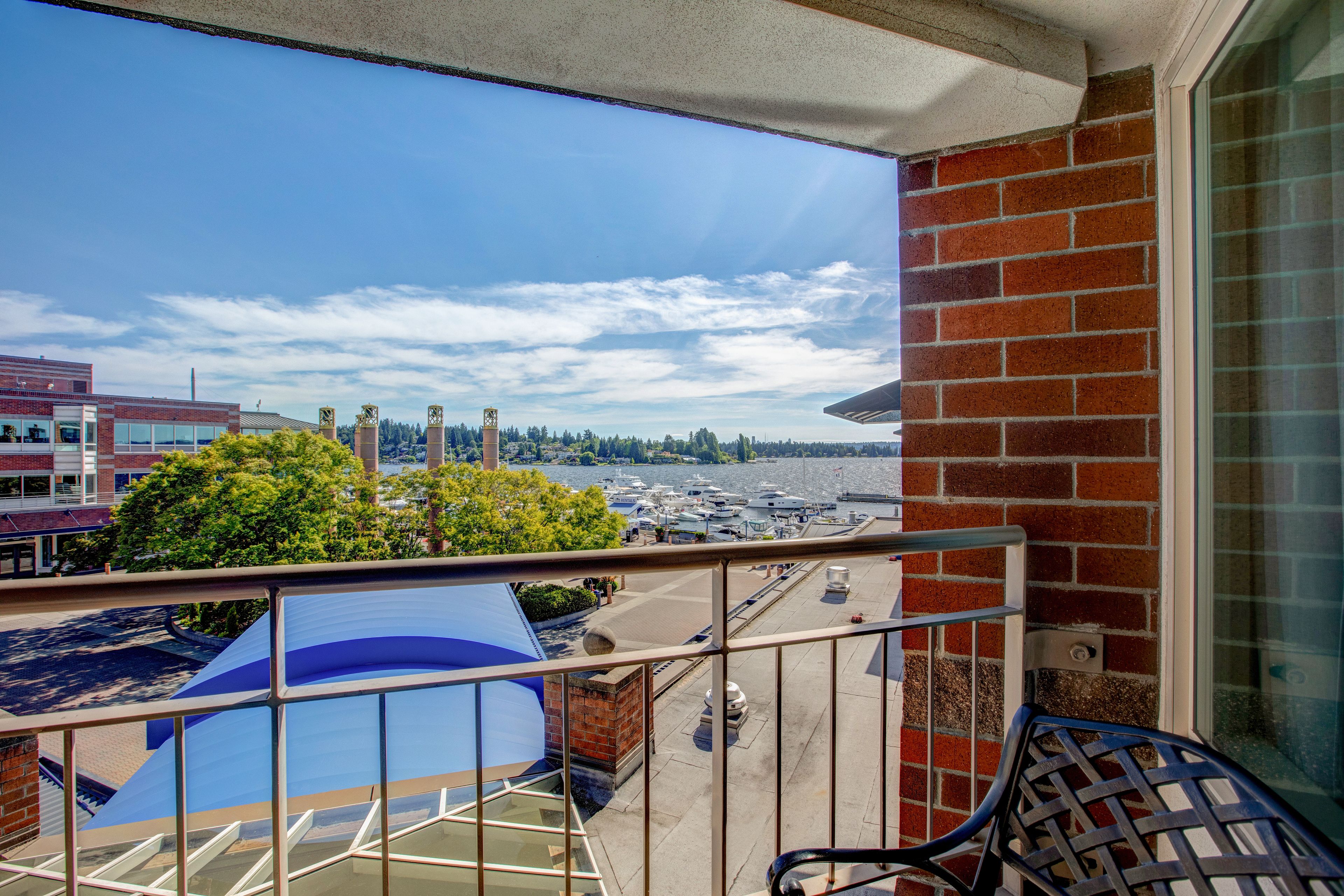 A balcony with a view of a marina and boats, a brick wall, and a blue chair.