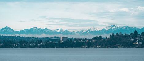 A coastal cityscape with mountains in the background and a calm body of water in the foreground.