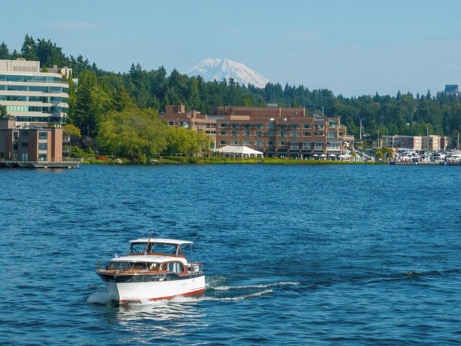 A boat on a lake with buildings and a mountain in the background.
