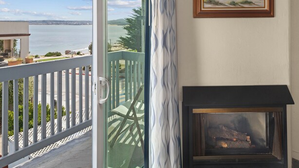 A balcony with a view of the sea, a fireplace, and a framed painting.